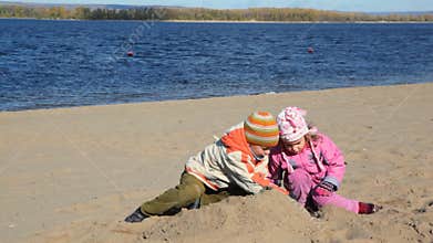 boy and little girl is digging in sand of beach