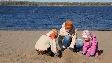 young woman, boy and little girl constructing sand
