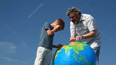 senior with his grandson stand and study Earth by