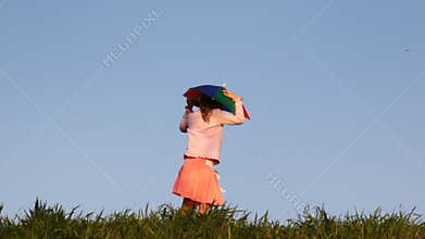 nice little girl in hat as rainbow umbrella turns