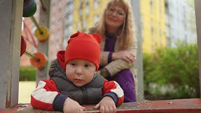 Slow motion. A small child plays on an abacus while standing on a playground in a city park on a spring day. In the