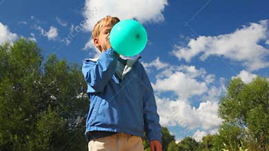 boy inflating blue balloon in