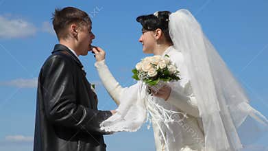 bride with bouquet feeds with sweets her groom