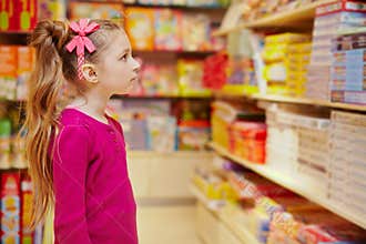 Little girl wonderingly looks on abundance of board games