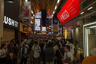 Crowd of people and baseball fans gather on a commercial street at night in Osaka, Japan.