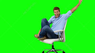 Smiling man cheering and turning on swivel chair on green screen