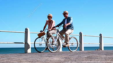 Active seniors going on a bike ride by the sea