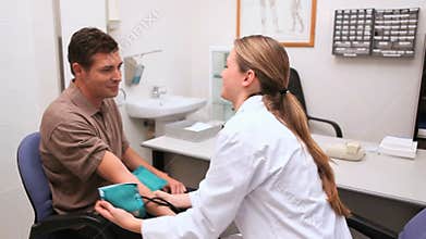 Smiling doctor measuring the blood pressure of his patient