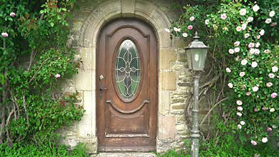 Charming rustic wooden arched front door framed by ivy and blossoms