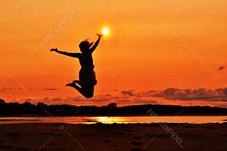 Silhouette of a woman jumping at sunset, touching