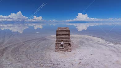 A young girl explores the vast expanse of the Salar de Uyuni salt flats in Bolivia, under a clear blue sky