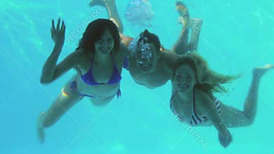 Three friends diving into swimming pool and waving