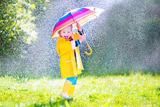 Funny toddler with umbrella playing in the rain