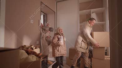 Man carries moving boxes into new apartment room with family