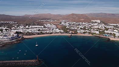 Aerial bay on Lanzarote with resorts, breakwaters, and lighthouse