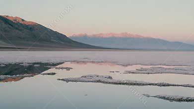 Desert salt flats reflecting mountains at sunset