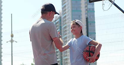 Father gives support to son after game. Happy boy shakes hand with dad. Family support builds confidence on court. Man