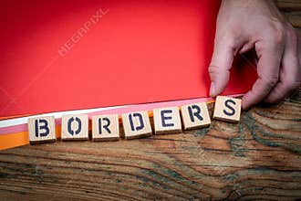 BORDERS Migration Control Concept Shown With Wooden Letter Blocks And Hand