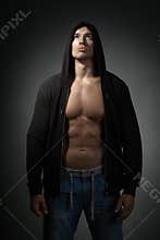 Strong man wearing black hoodie isolated on dark