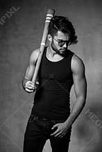 fashion man model with a baseball bat posing dramatic against grunge wall