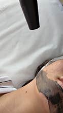 Young woman getting carbon laser facial at beauty clinic. Professional skincare