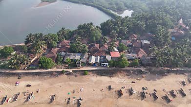 High-angle aerial view of a traditional fishing village on a sandbar between the ocean and a river at Kelus Kalvi Beach, India