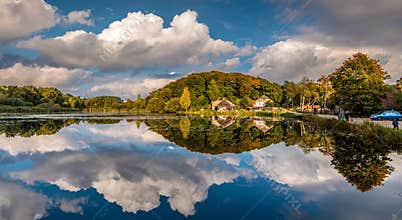 Lakeside Reflections with Trees, Clouds, and Quiet Human Presence