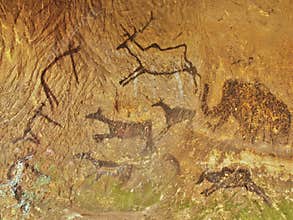 Abstract children art in sandstone cave. Black carbon paint of human hunting on sandstone wall