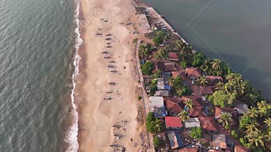 High-angle aerial view of a traditional fishing village on a sandbar between the ocean and a river at Kelus Kalvi Beach, India