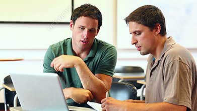 Teacher helping mature student in computer class on the laptop