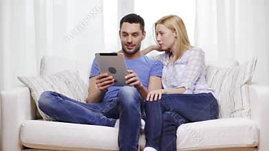 Smiling happy couple with tablet pc at home
