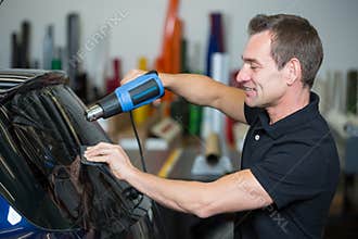 Car wrapper using heat gun and squegee for tinting window