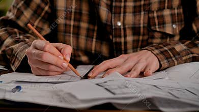 Person in Plaid Shirt Drawing Architectural Plans on Desk