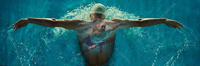 Male swimmer in white cap performs butterfly stroke with overlay of underwater action on back. Banner