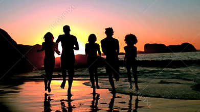 Friends running into the sea under the dusk