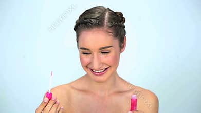 Smiling young woman applying lipgloss on her lips