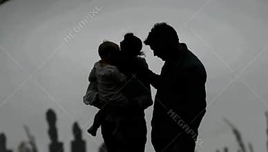 Silhouette of a family with a young child standing together against a bright background creating a sense of unity and love