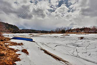 Winter landscape view of Baskatong Reservoir with a blue rowboat on the beach