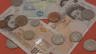 Sterling UK cash and coins rotating a red background.