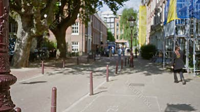 City street scene with a woman walking amidst blurred buildings and trees, capturing a warm european ambiance with defocused,