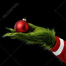 Green Furry Hand Holding Red Christmas Ornament on Black Background
