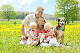 Portrait of Happy Family and Dog in Flower Meadow