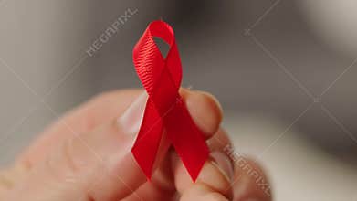 Hand creating a red ribbon for aids awareness