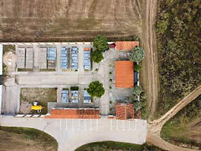 View of a rural building complex with parking area and surrounding landscape in daylight