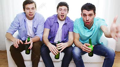 Happy male friends with beer watching tv at home