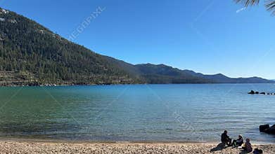 Wide scenic view of Sand Harbor beach cove with emerald water and pine forest background