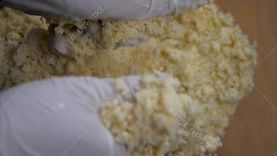 Hands mix buttery crumbs for pie dough