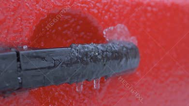 Car door handle covered in ice with icicles forming