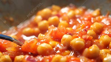 Cooking chickpeas in tomato sauce on a stovetop