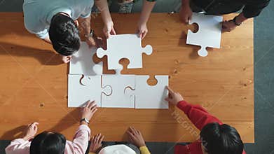 Top down view of business people assemble jigsaw puzzle on table. Convocation.